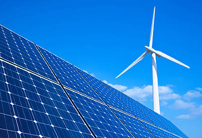 Solar panels and wind turbine against blue sky.